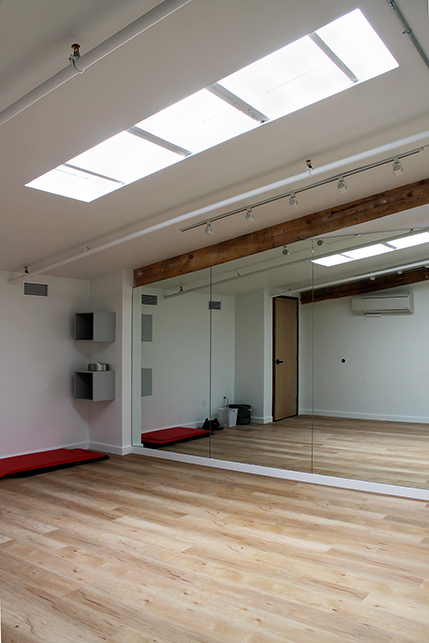 A smaller dance studio featuring skylights and wooden floors offering space for additional classes